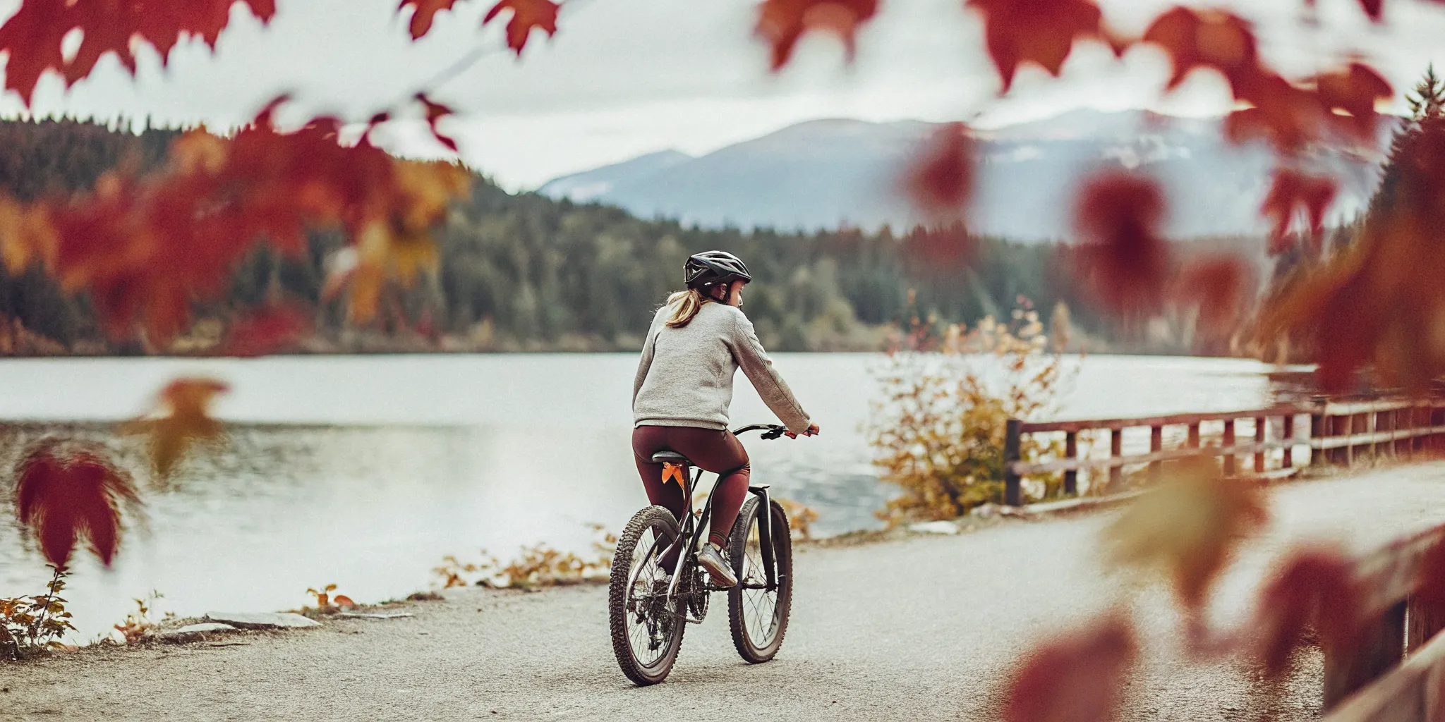 Golden autumn Whistler valley trail with trees displaying red and yellow fall foliage, calm lake and mountain views in the background
