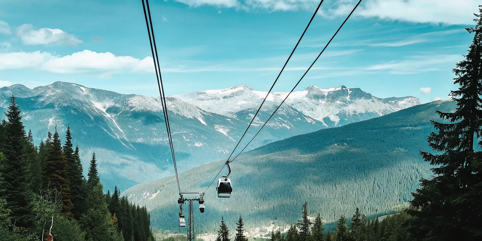 The iconic PEAK 2 PEAK Gondola crossing the massive valley span between Whistler and Blackcomb mountains under a clear summer sky