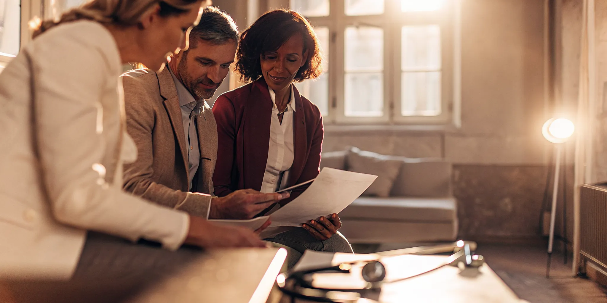 A CPA advisor and two business owners reviewing financial planning documents together in a bright modern office