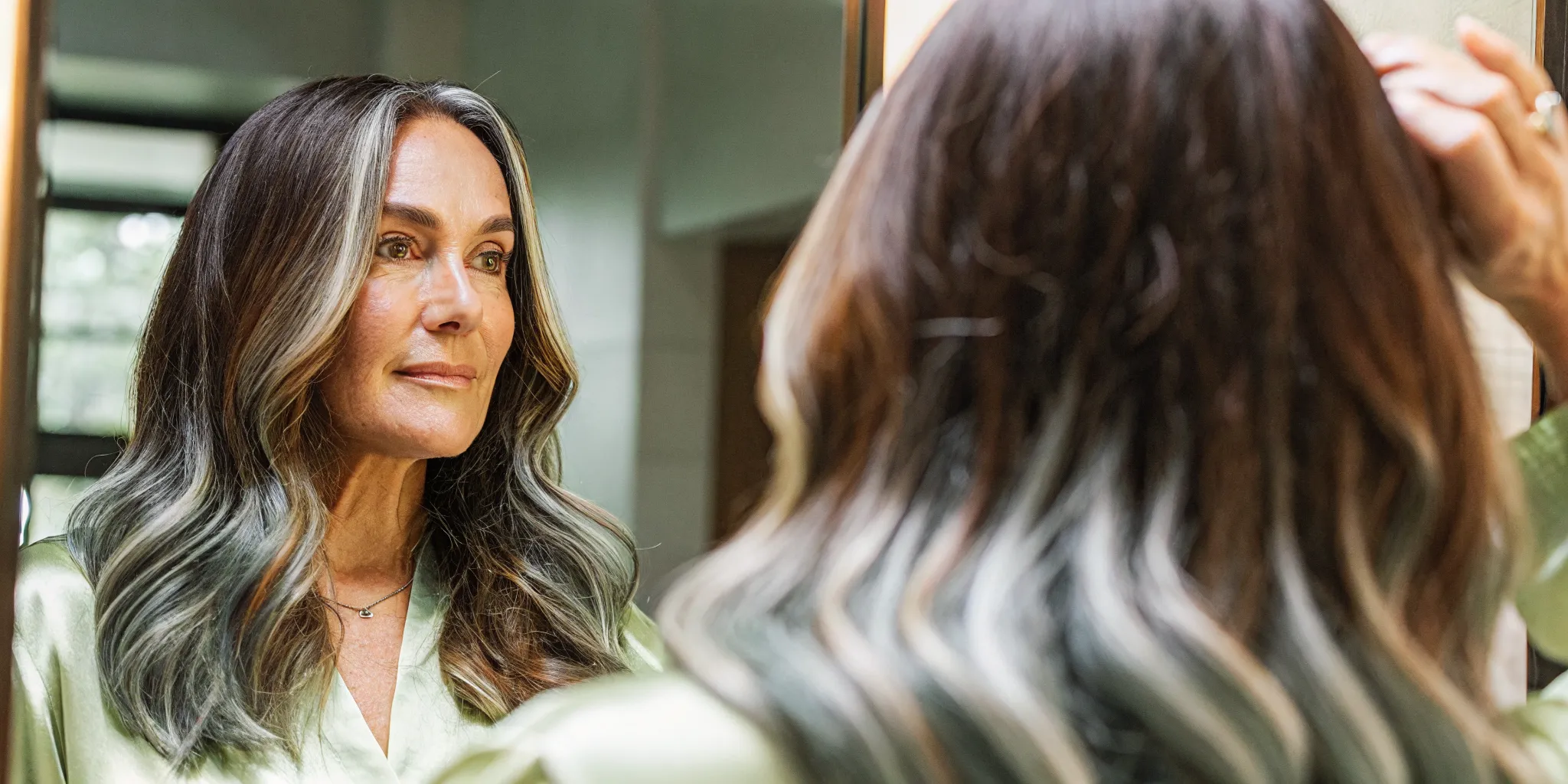 Woman with healthy salon-colored brunette hair showing vibrant gray coverage with soft silver blending at the roots