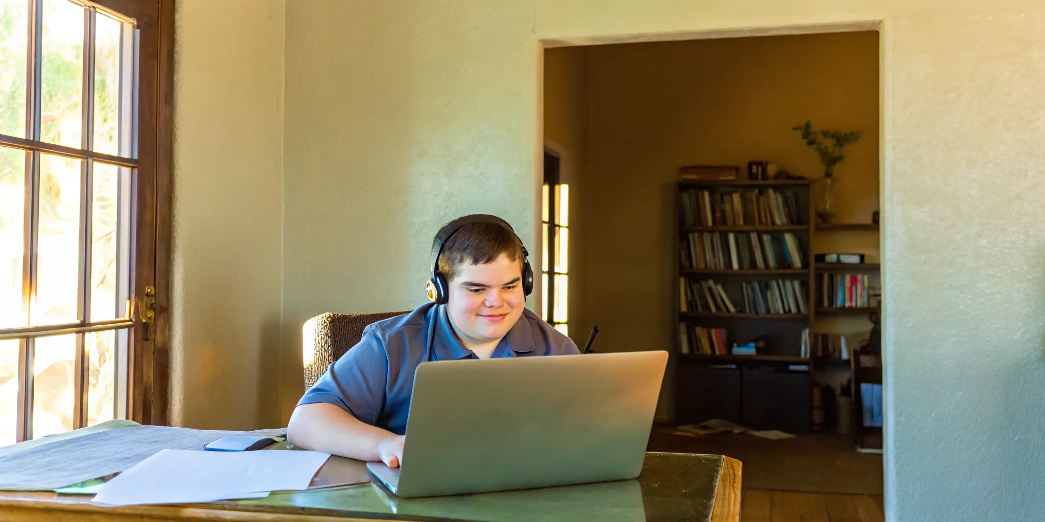 Teenage student taking an online SAT prep session from home, focused on laptop with headset