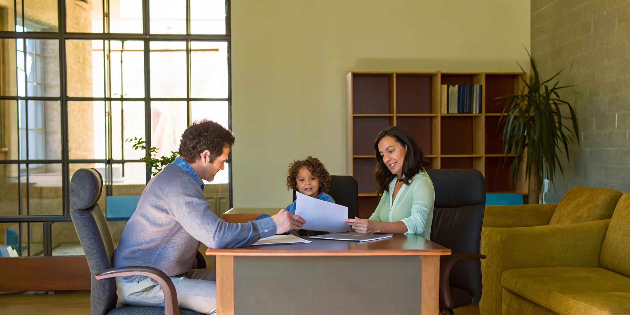 Educational consultant reviewing college application materials with a student and parent in a professional Atlanta office setting