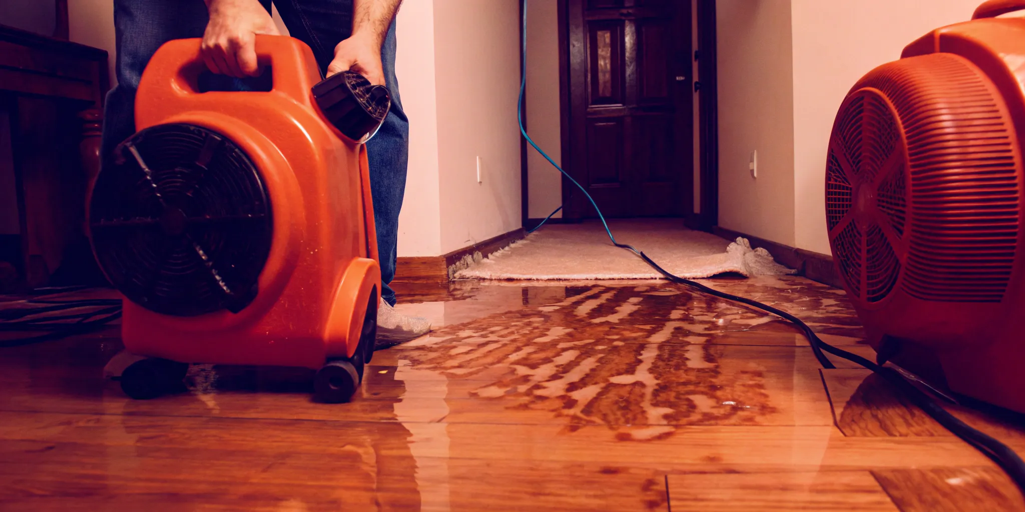 Water damage restoration technician using professional air movers to dry water-damaged floors in a Bakersfield home