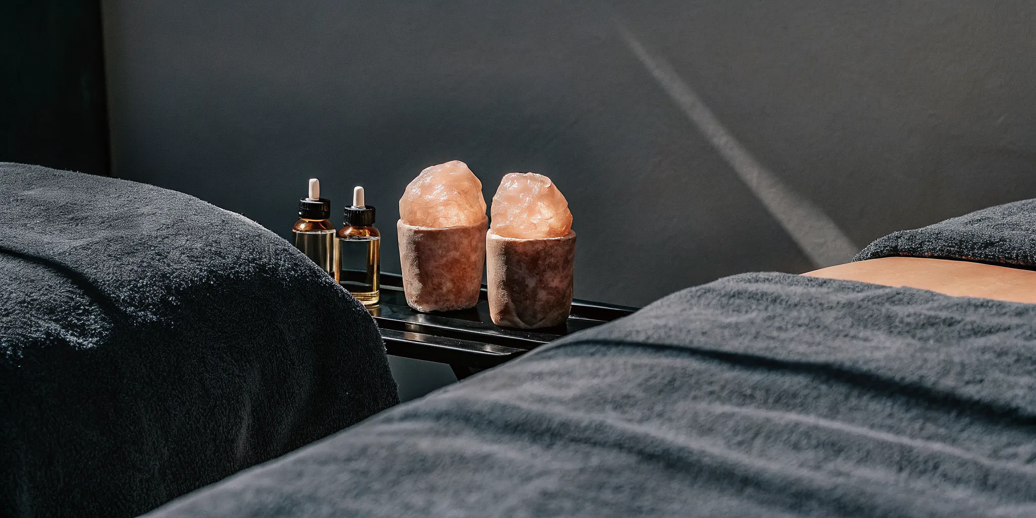 Himalayan salt stones and CBD massage oil prepared beside a massage table