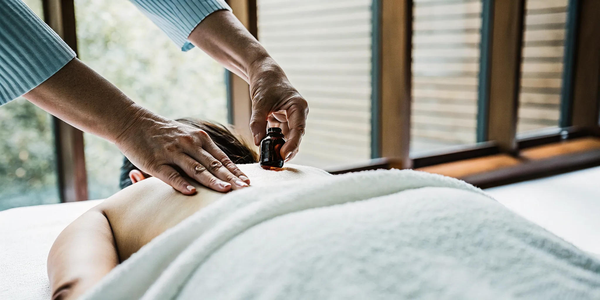 Massage therapist applying CBD oil to a guest's back muscles during a therapeutic session