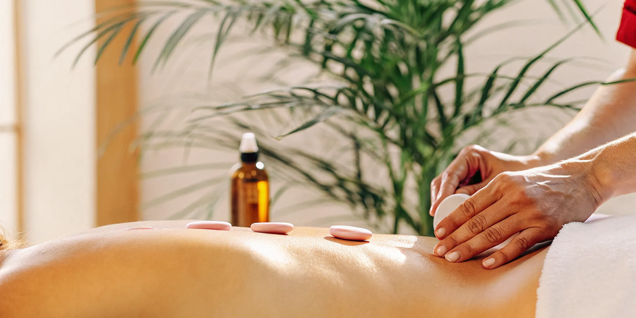 Therapist using smooth Himalayan salt stones during a warm massage session