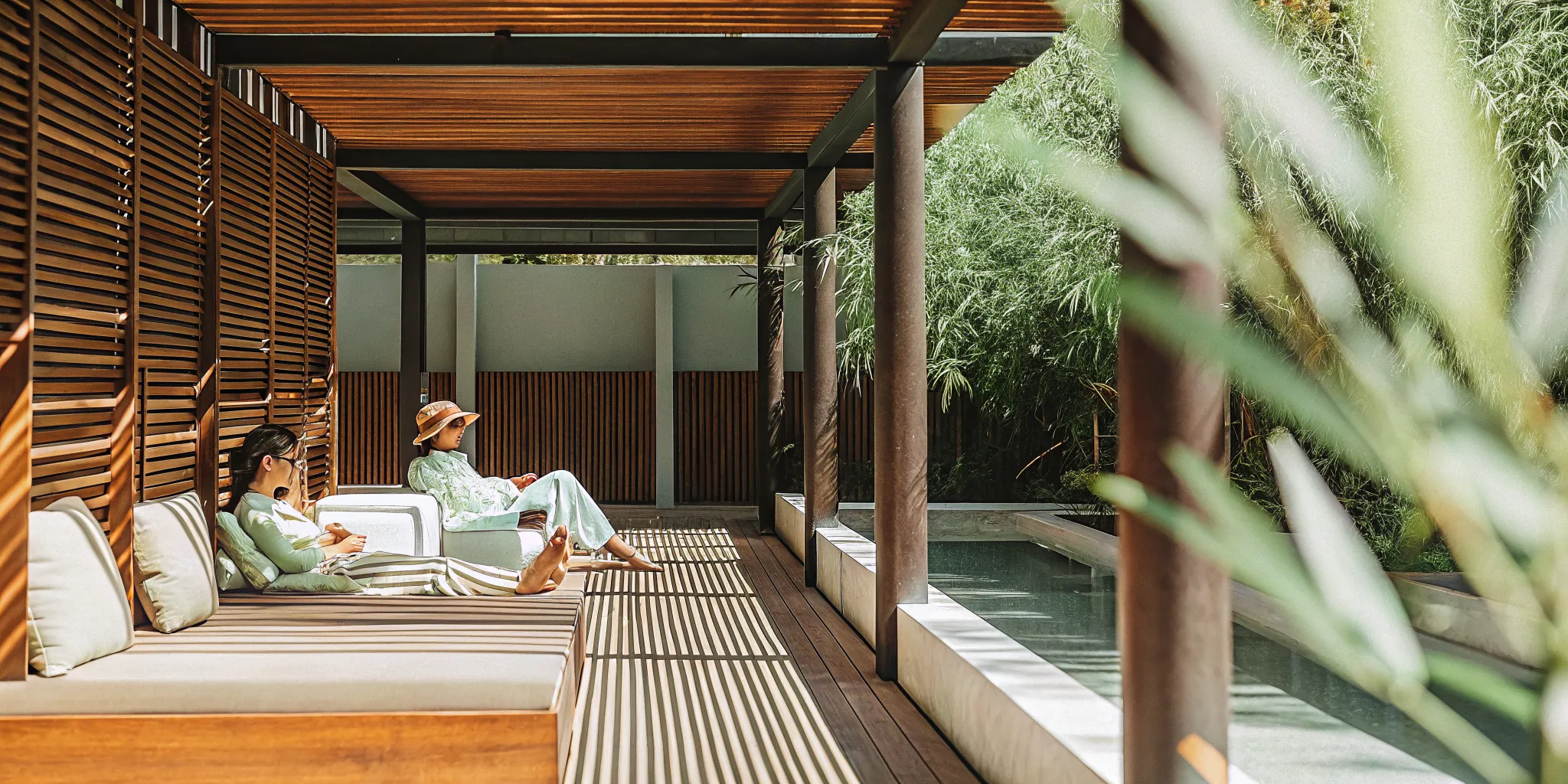 Commercial pergola creating shade beside a hospitality pool lounge