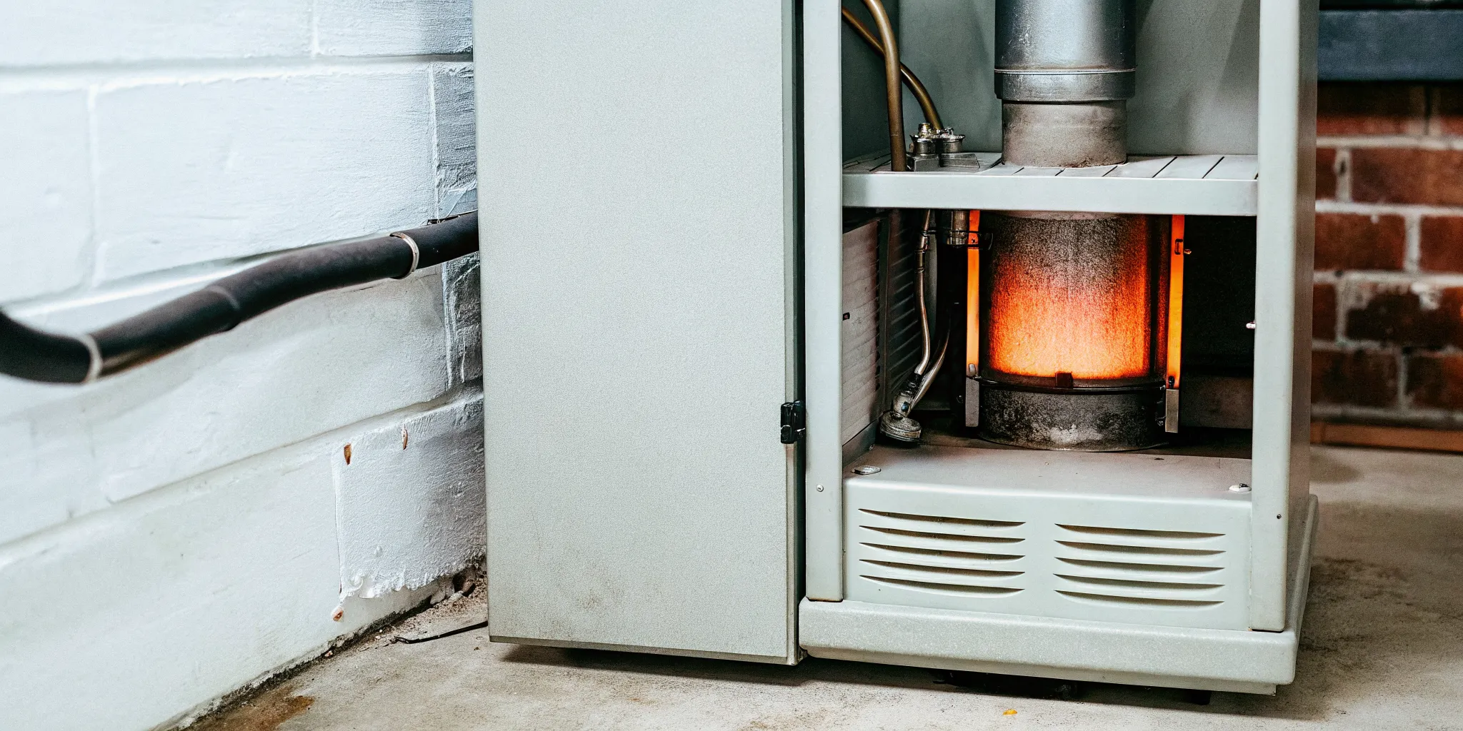 Modern gas furnace with electronic ignitor glowing orange inside a residential basement