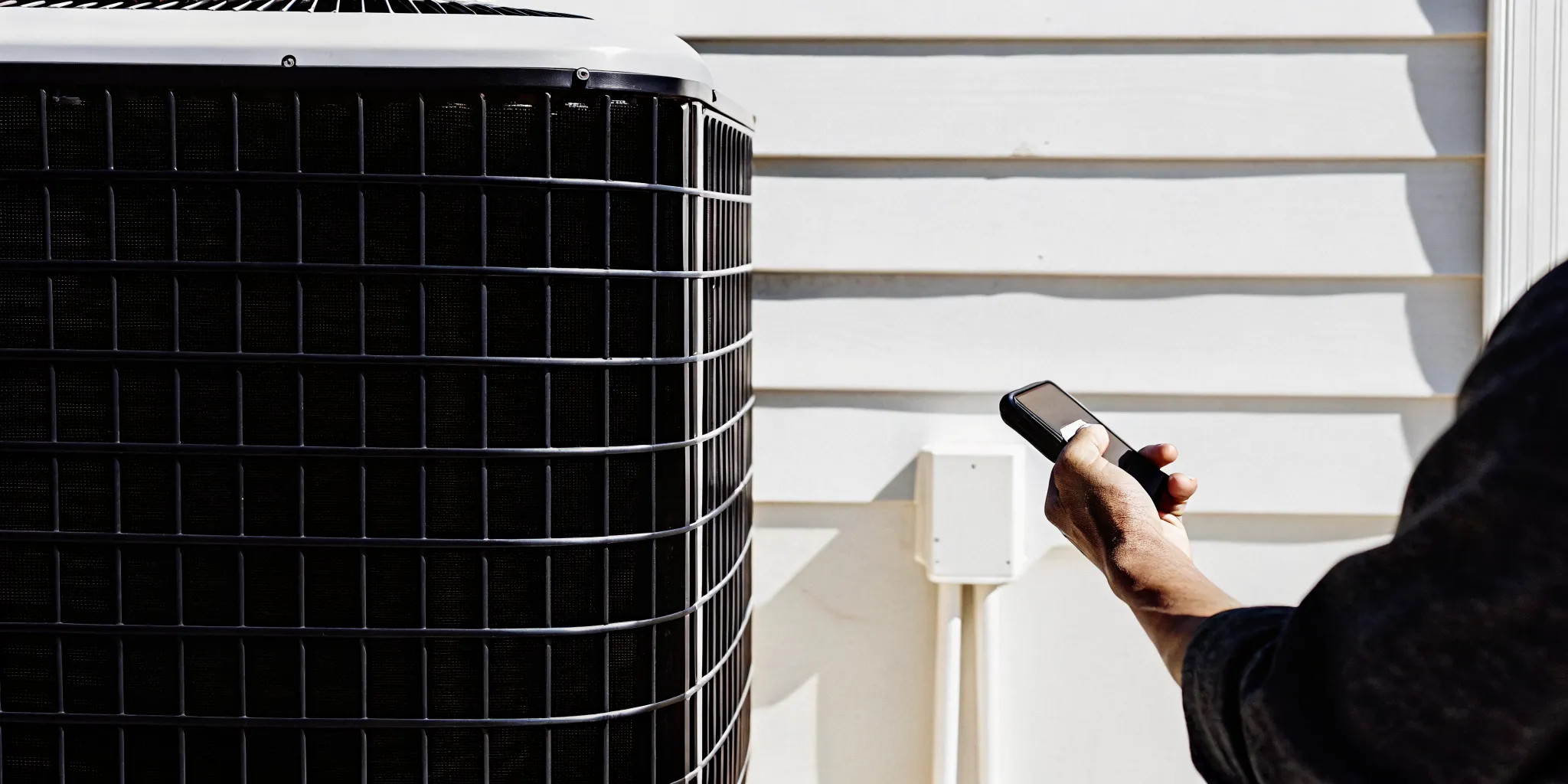 Homeowner checking thermostat settings for HVAC troubleshooting