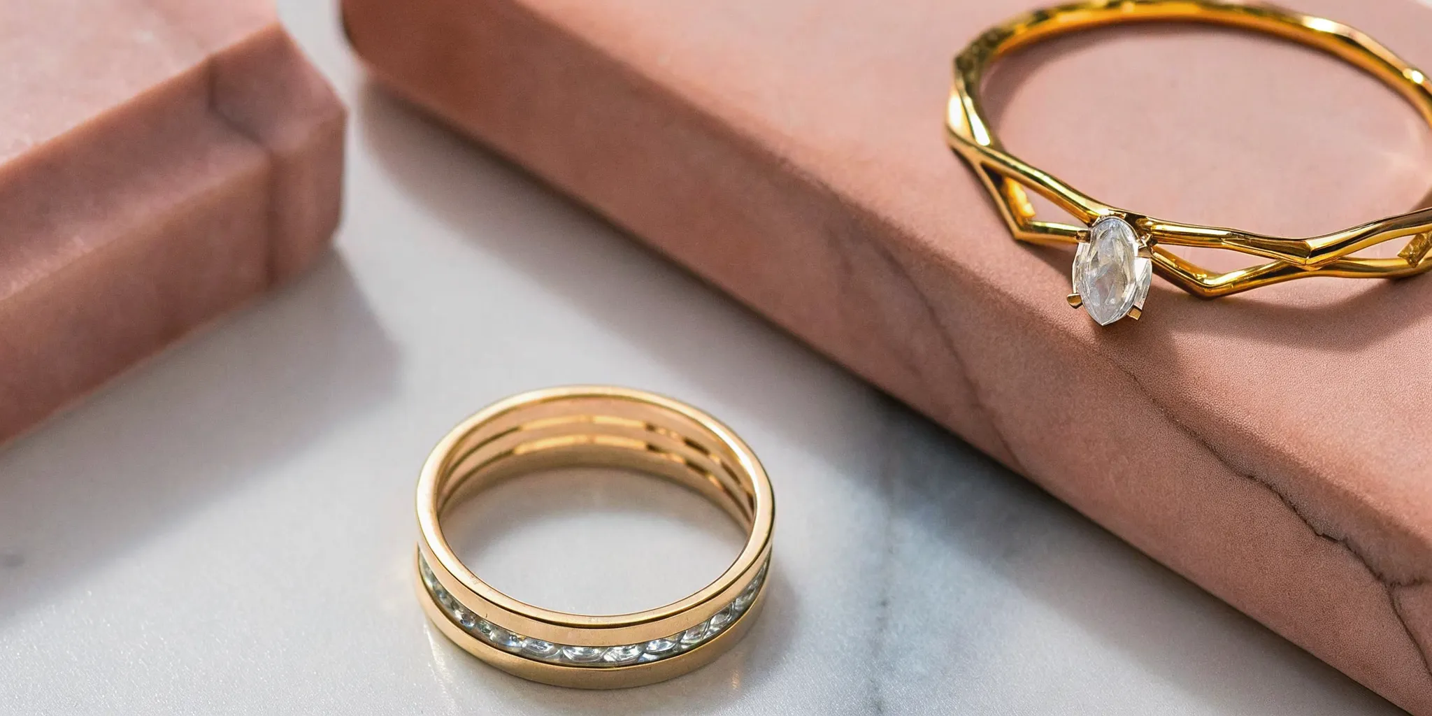 Curated contemporary jewelry flat lay featuring raw diamond ring, oculus gold band, and geometric diamond ring on marble surface