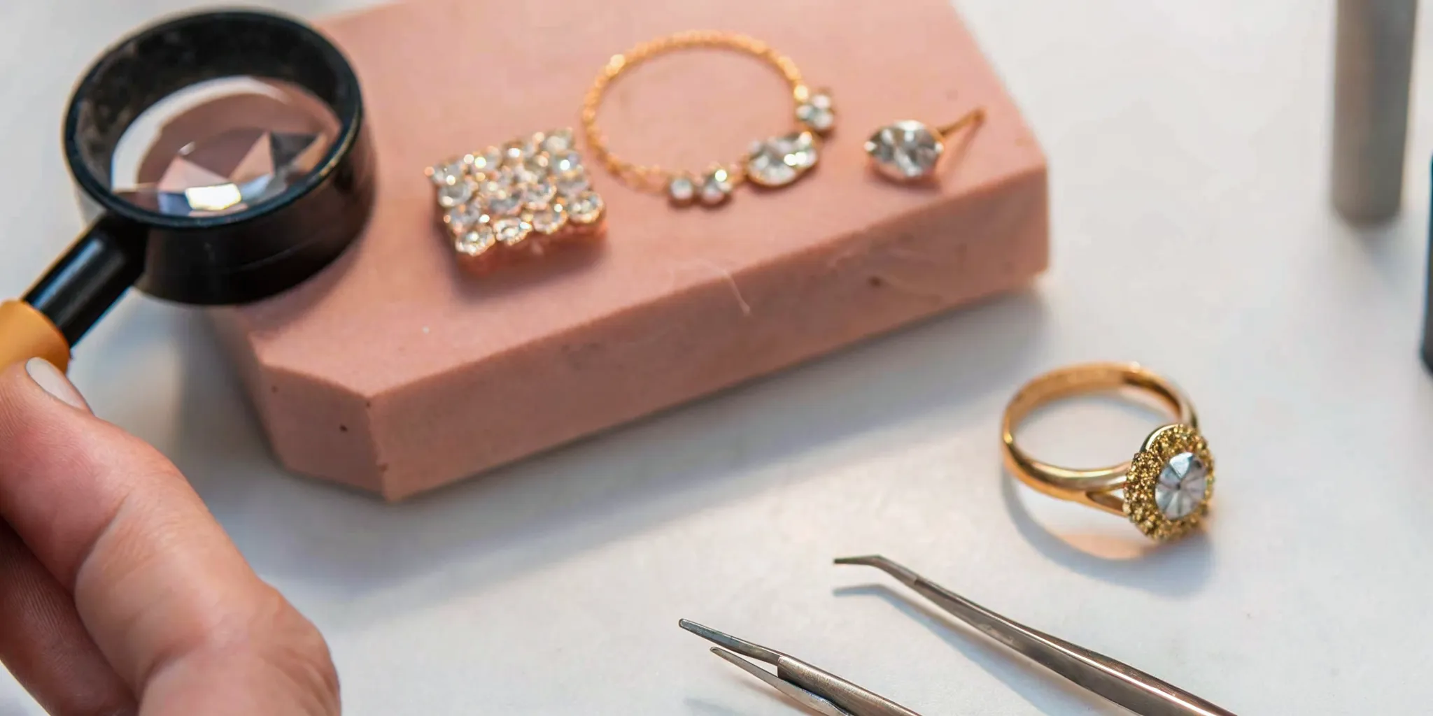 Jewelry redesign bench with loose diamonds, gold bands, and wax carving model on felt surface