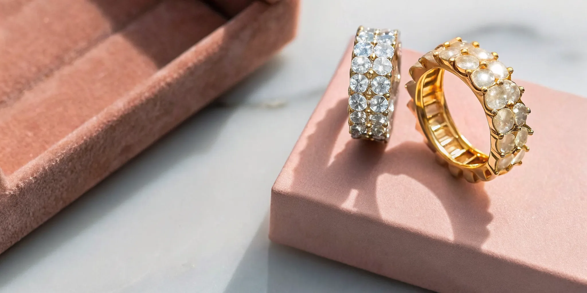 Diamond anniversary ring and gold wedding band on marble surface
