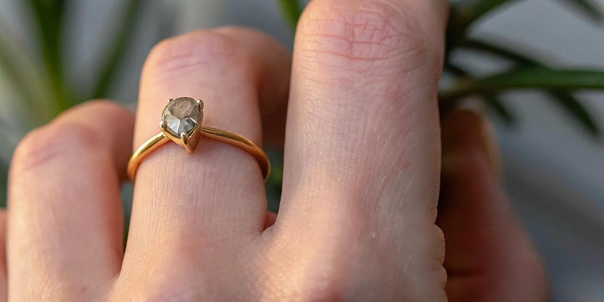 Handcrafted ring with raw diamond on finger, natural light highlighting artisan metalwork and unique stone setting