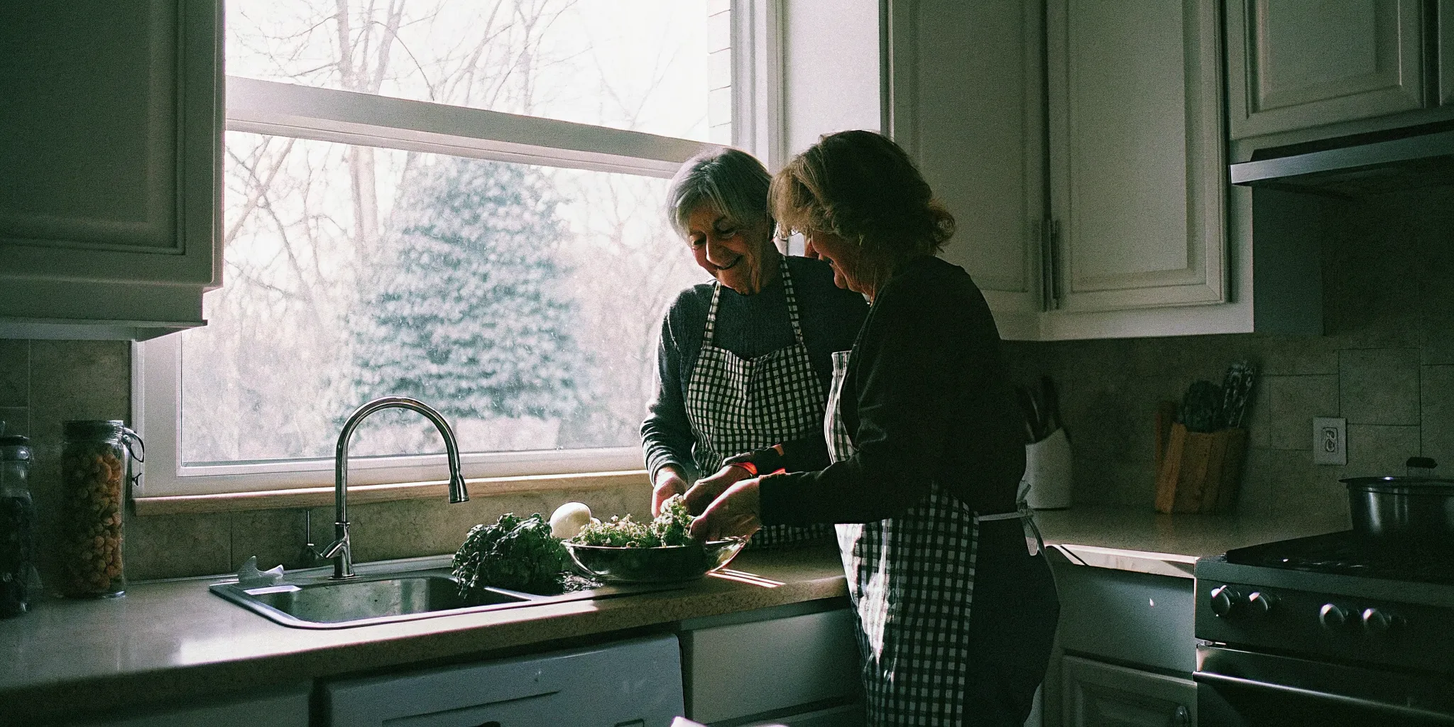 Caregiver and senior woman preparing a healthy vegetable salad together in a bright kitchen