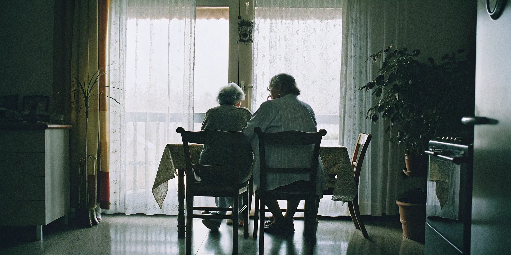 Family caregiver and elderly parent having a calm conversation at a kitchen table
