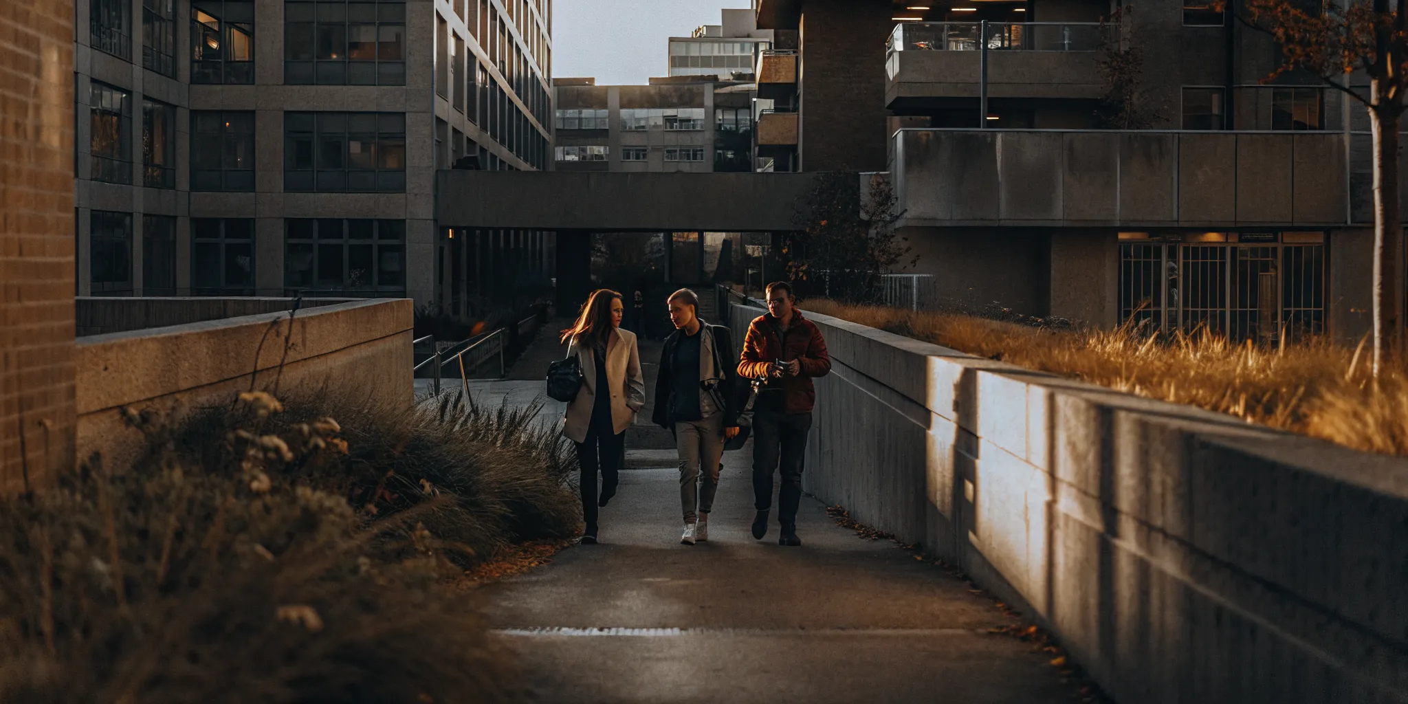 Students walking on a university campus pathway between classes with modern buildings in the background