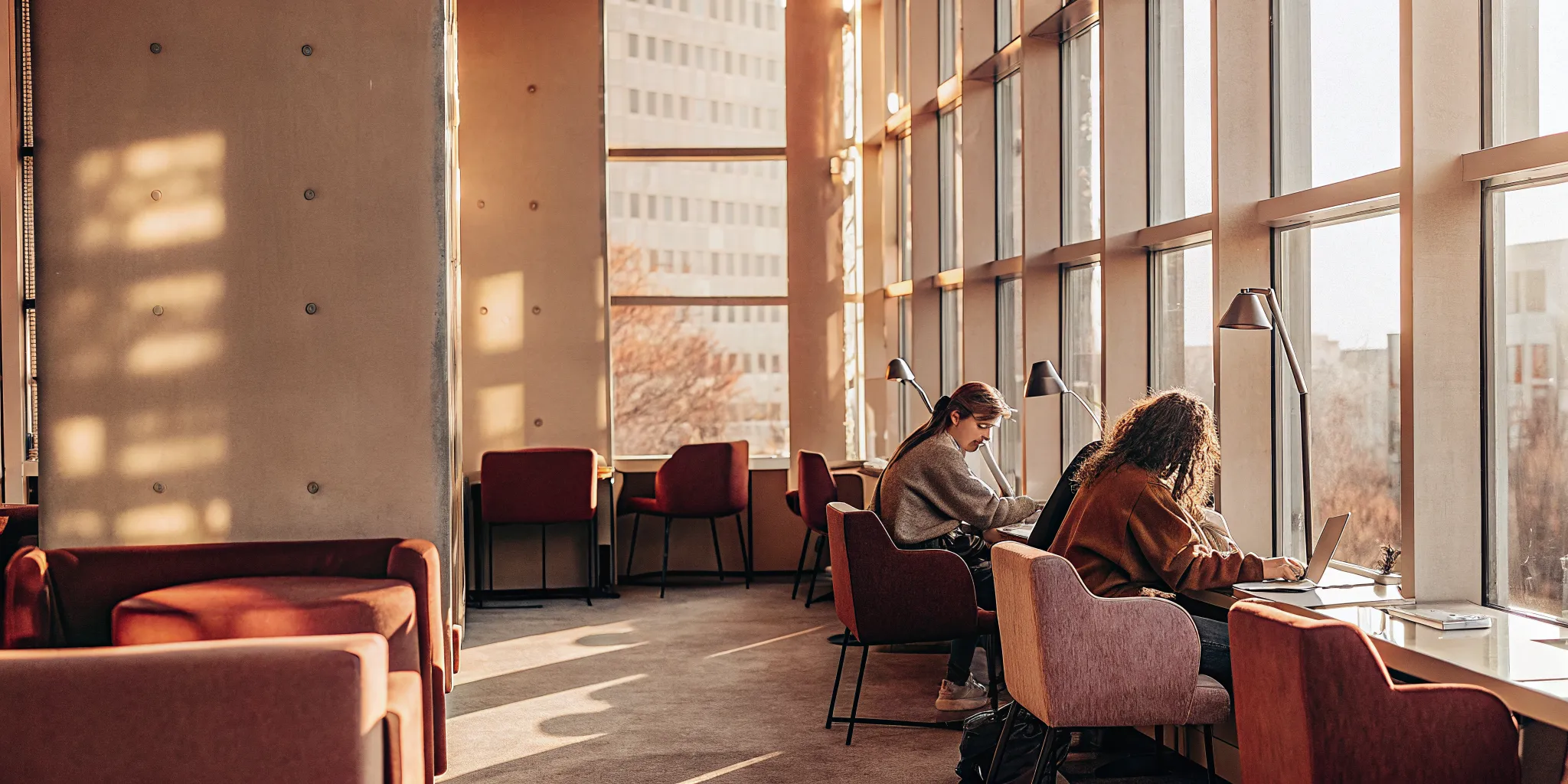 Modern student housing study lounge with natural lighting, ergonomic seating, and collaborative group spaces
