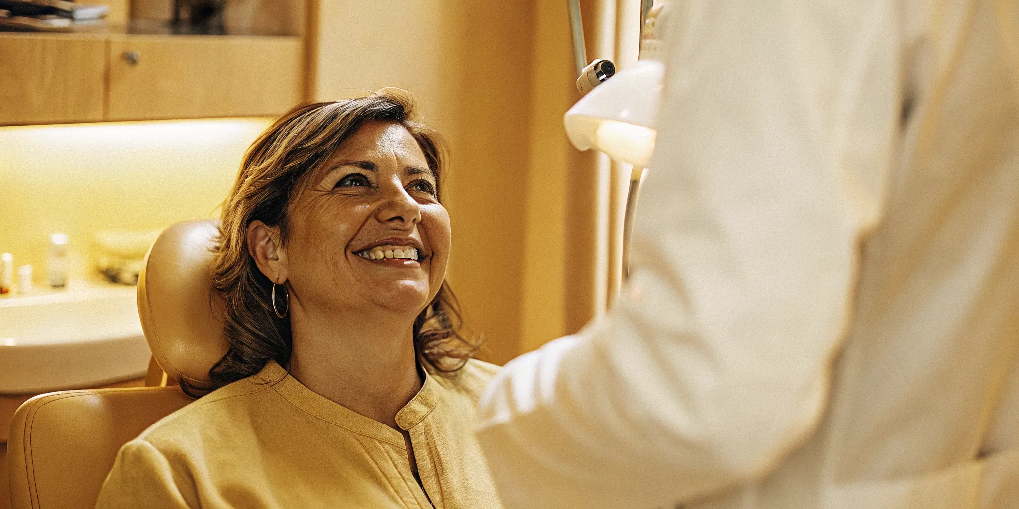 Happy patient smiling at a dental checkup after recovering from All-on-4 dental implant surgery at Lowell Family Dental Practice