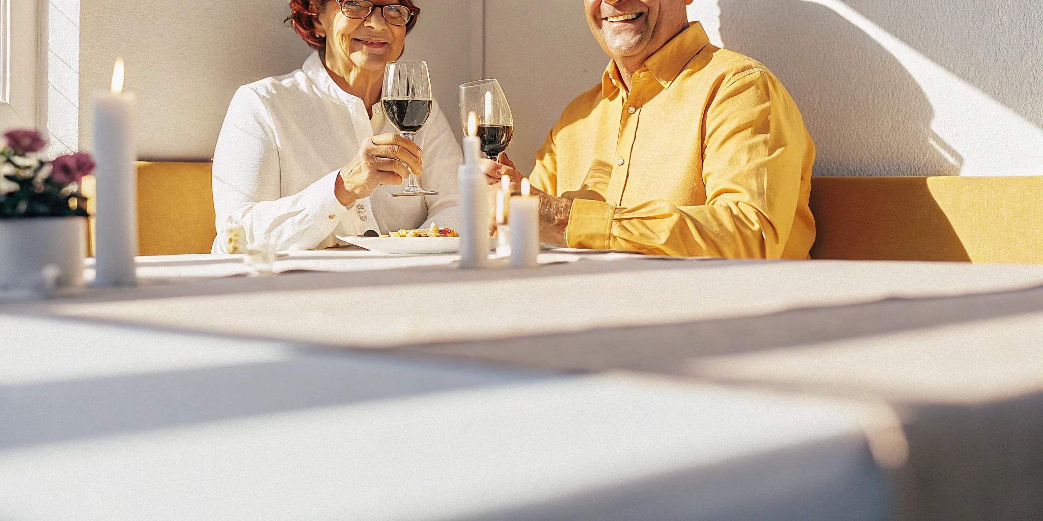 Happy older couple enjoying a meal together after receiving implant-supported dentures, smiling with confidence
