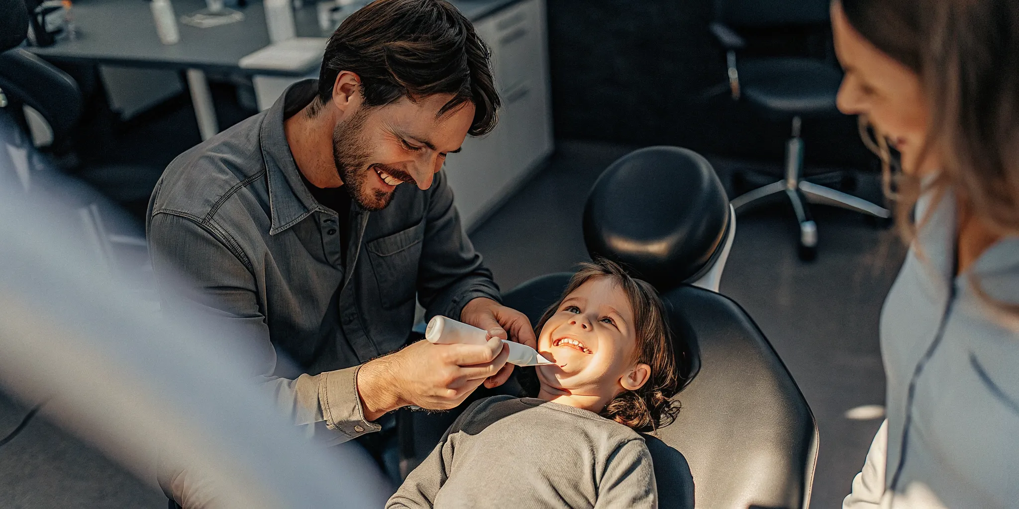 Pediatric dentist applying a dental sealant to a child's tooth in a bright Lowell dental office