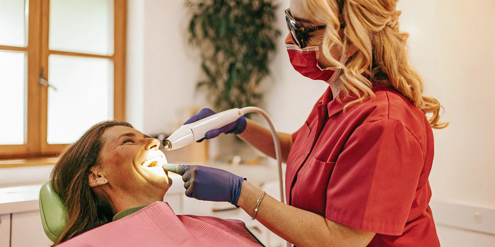 Dental professional performing teeth whitening treatment on a patient in a modern dental office
