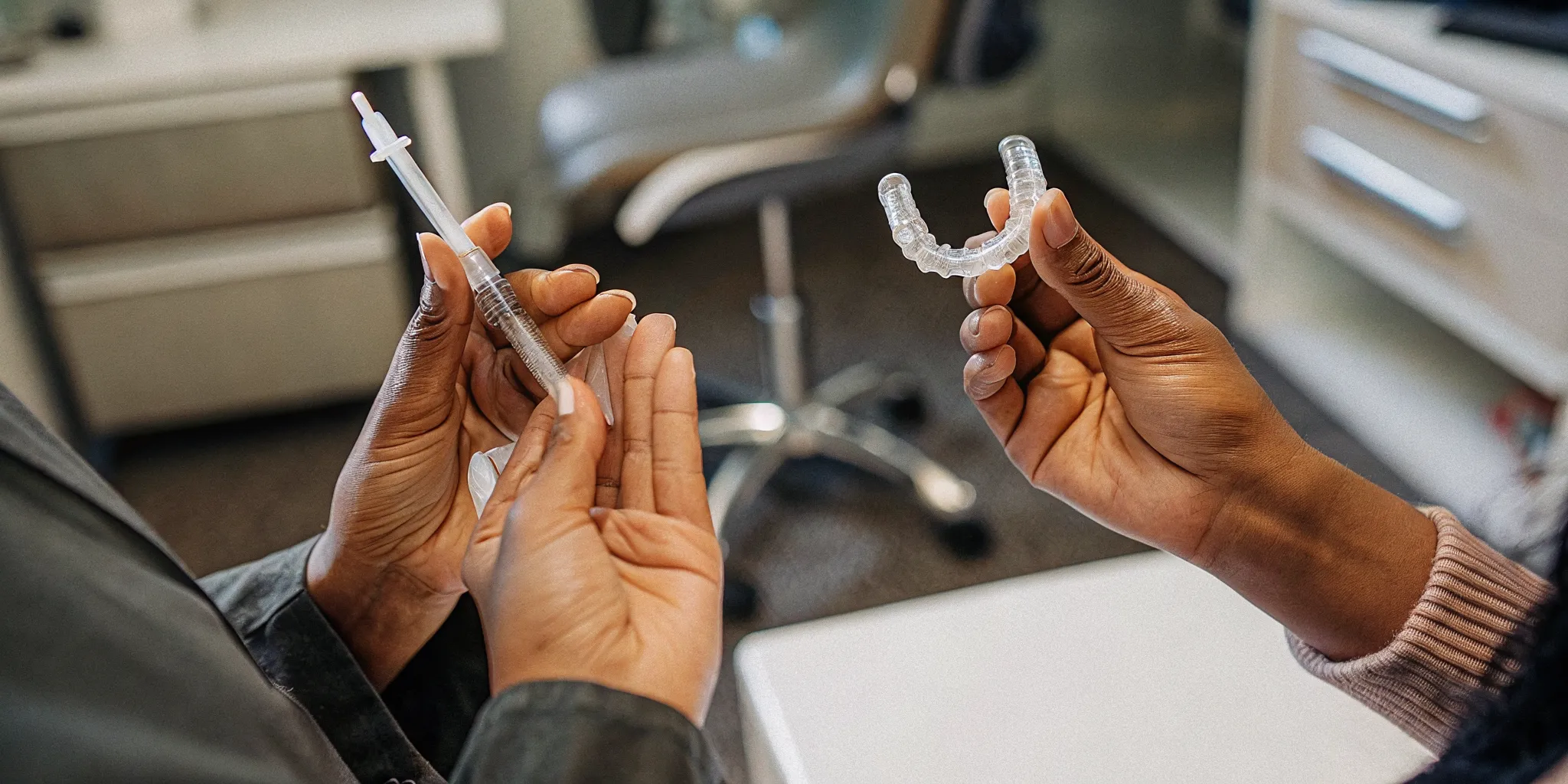 Custom take-home whitening trays and gel syringes on a dental office counter