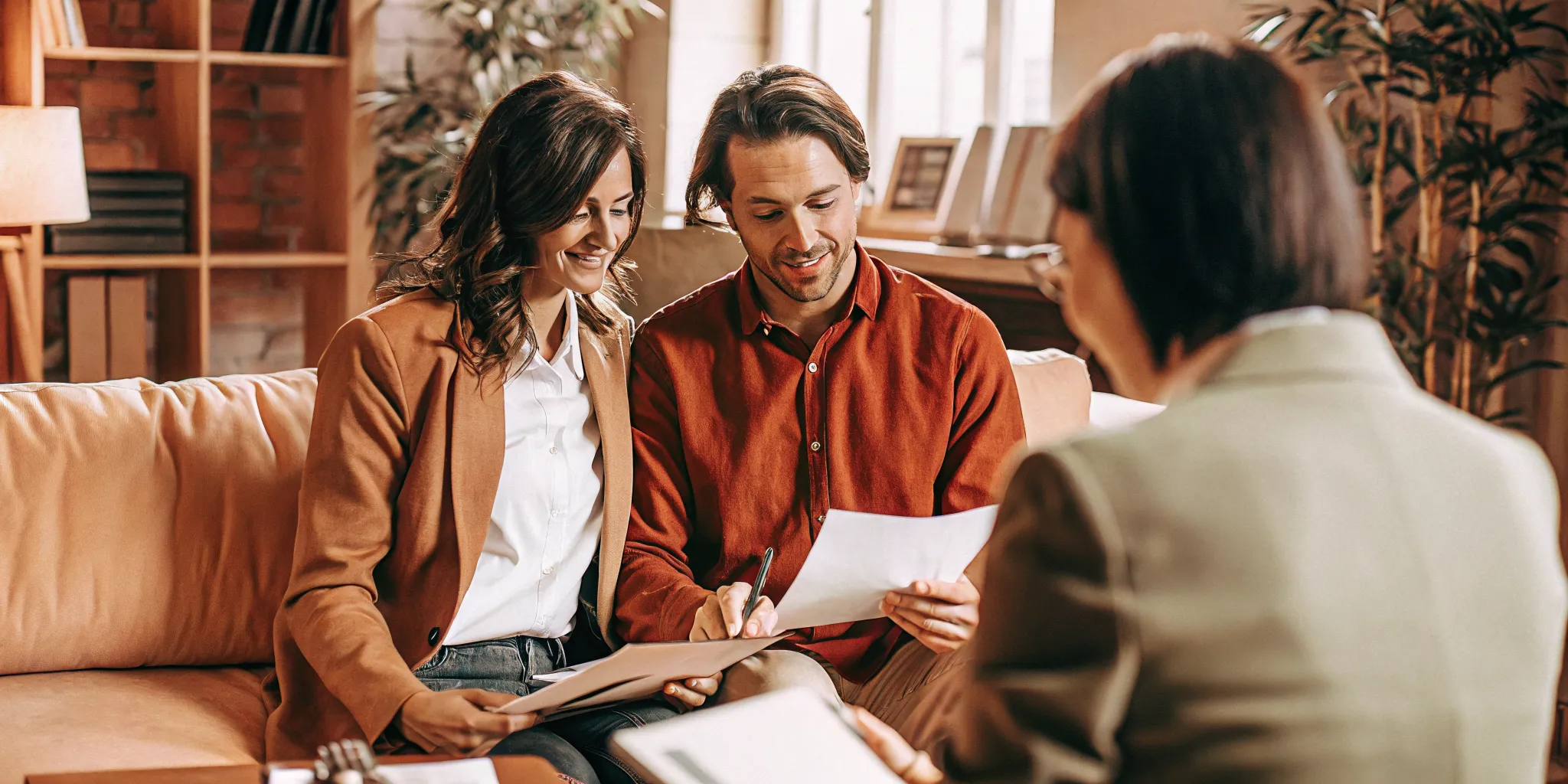 Professional couple meeting with a mortgage loan officer to review financing documents in a warm office setting