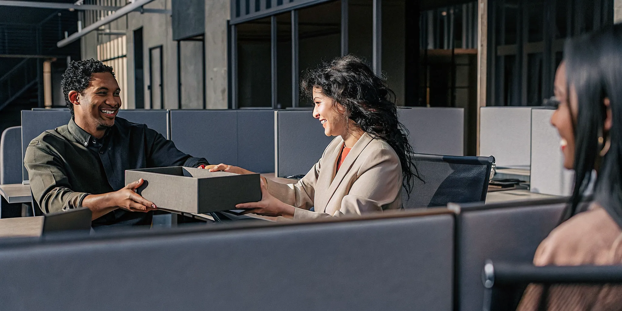 New employees in an office receiving branded welcome gift boxes as part of their onboarding experience