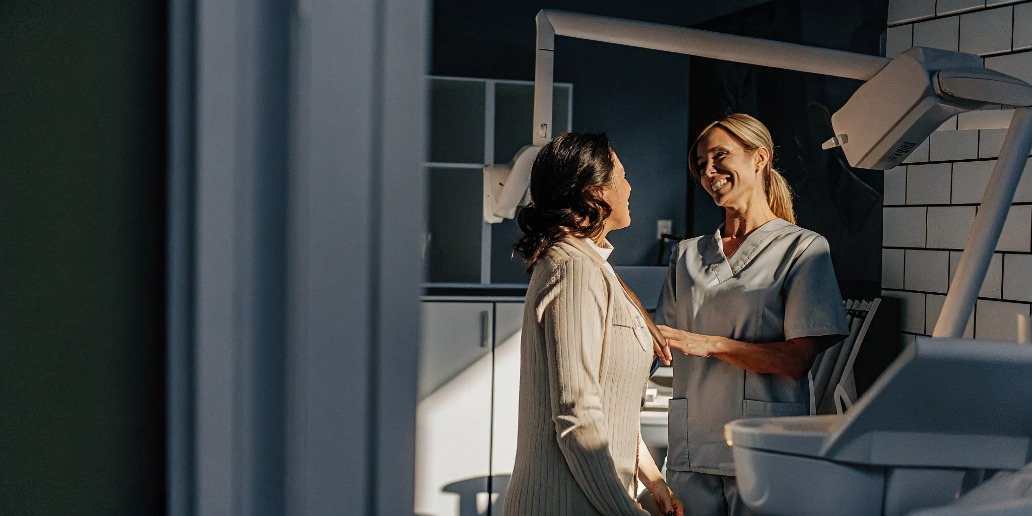 A modern dental office in soft natural light where a friendly dentist reviews a patient's healthy smile.