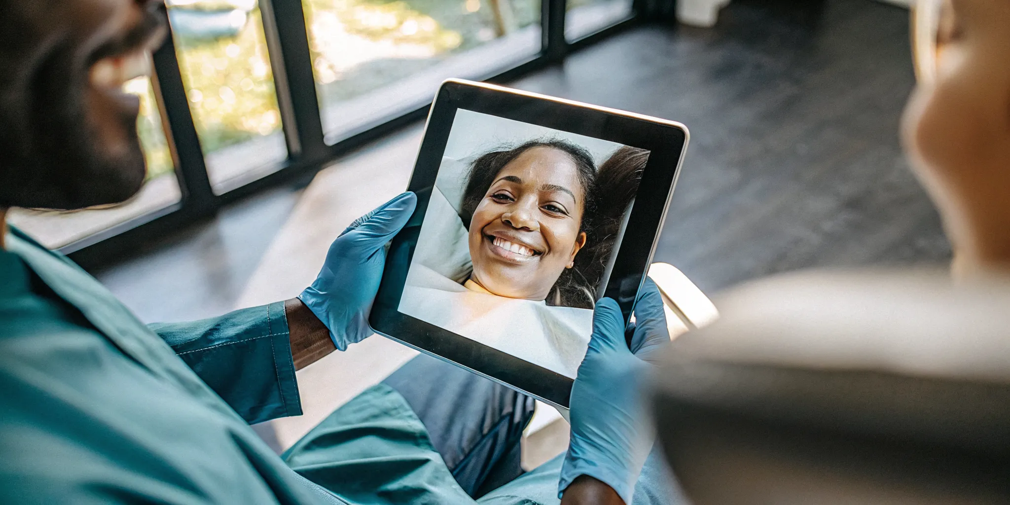 Cosmetic dentist showing porcelain veneer options to a patient on a digital screen in a modern dental office