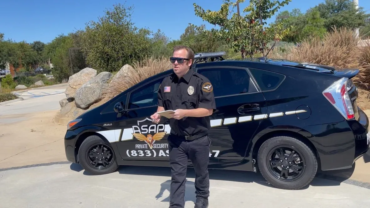 ASAP Security officer documenting a patrol observation beside a security vehicle