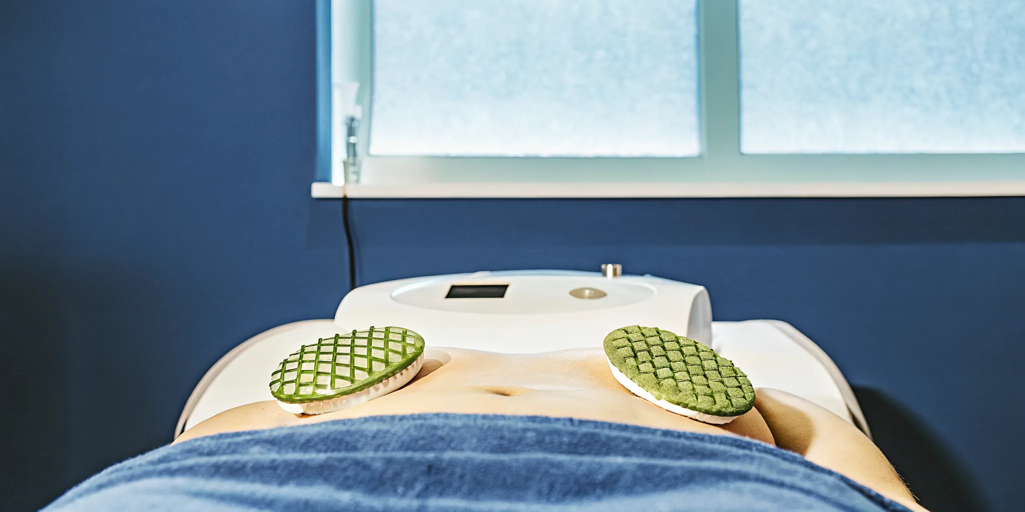 Verju green laser treatment paddles positioned on a patient's abdomen in a med spa treatment room
