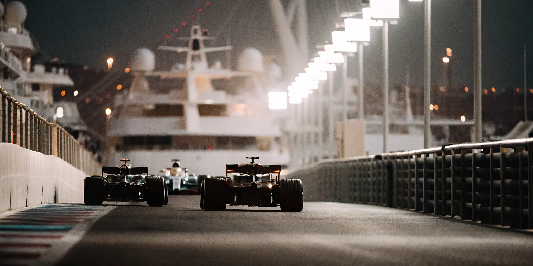 Formula 1 cars racing under twilight lights at Yas Marina Circuit in Abu Dhabi