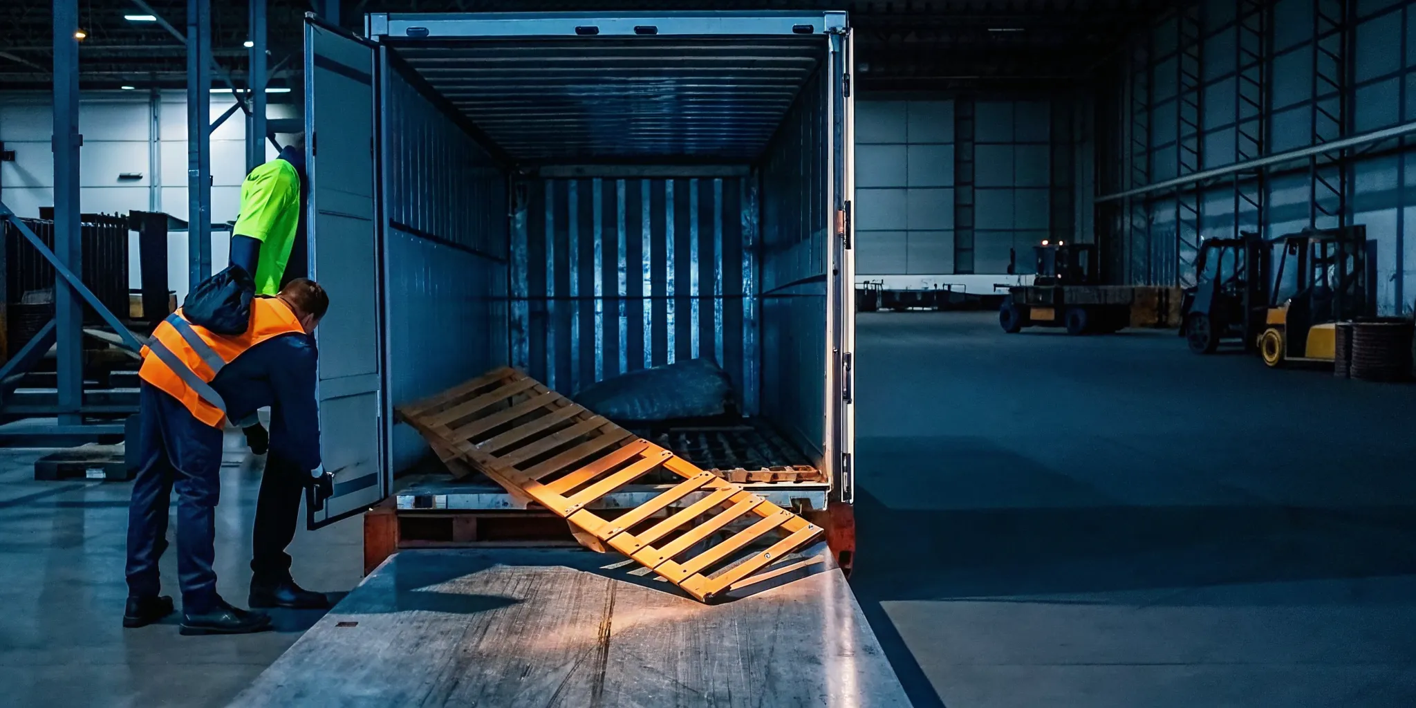 Warehouse dock worker inspecting a leaning palletized load beside an intact pallet