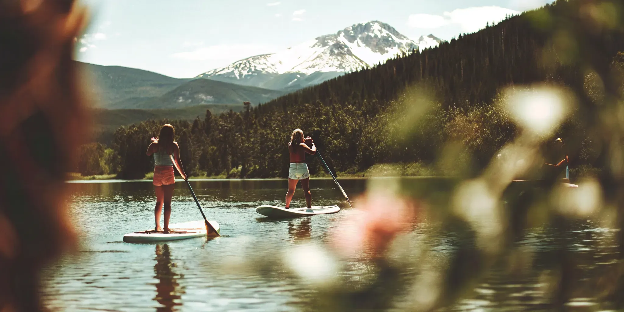 People paddleboarding on calm Lake Dillon water with mountain scenery in the background