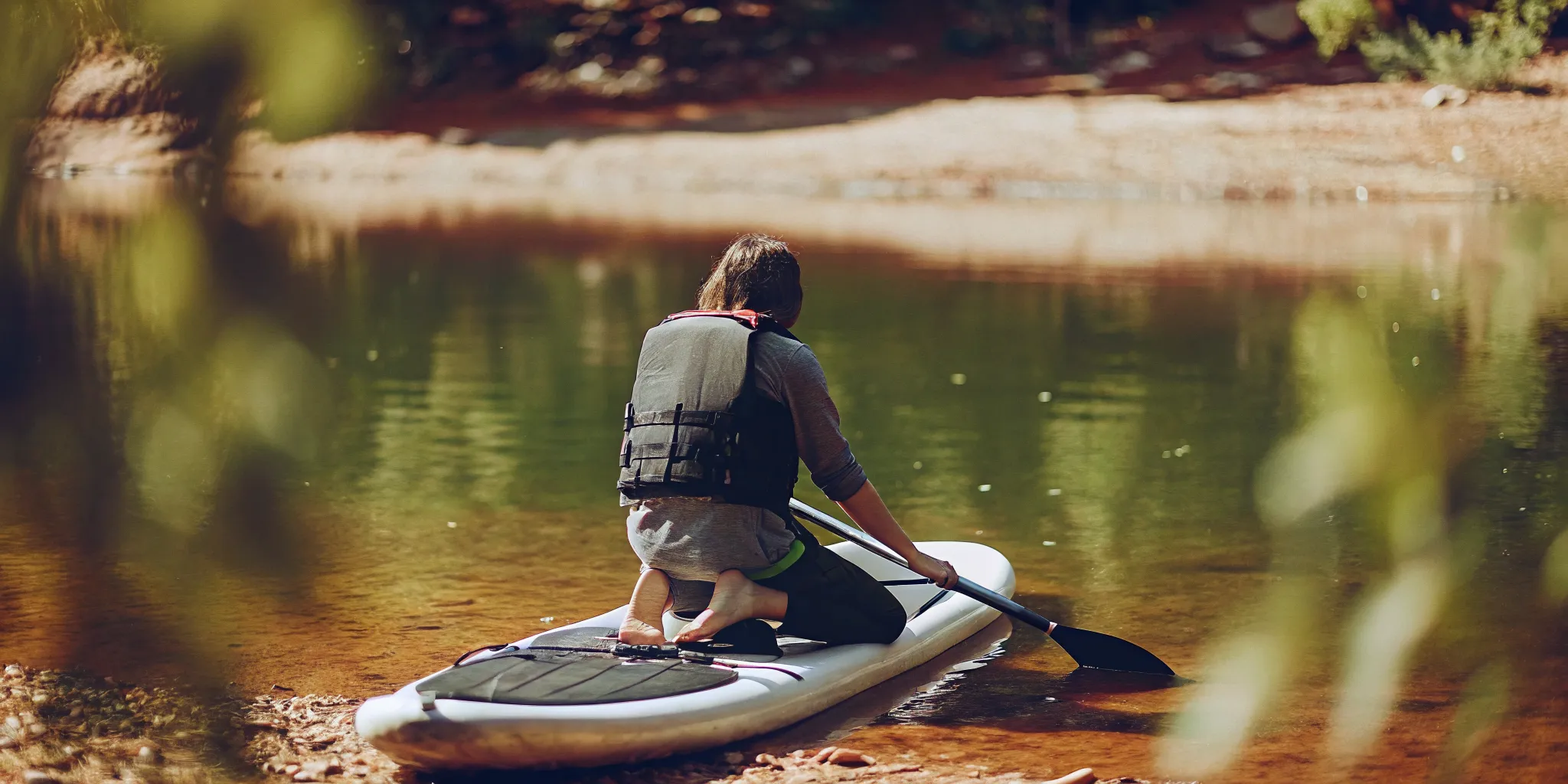 Beginner practicing how to stand up on a paddle board from a kneeling position