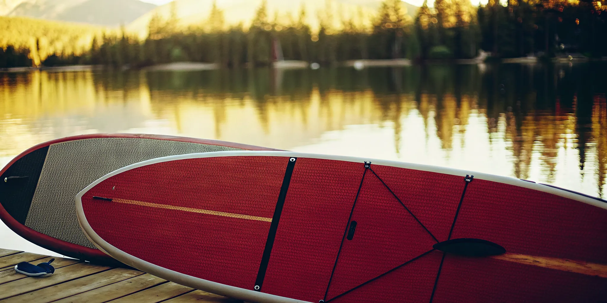 SUP boards and kayak on Lake Dillon dock with mountain peaks reflected in morning water