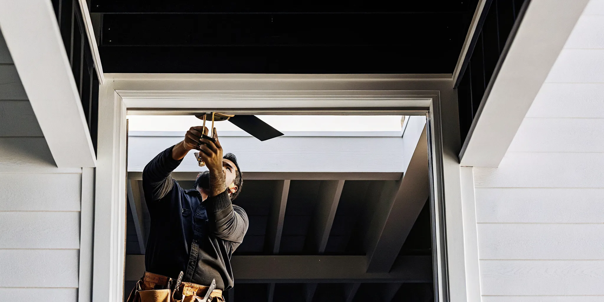 Electrician securing a fan-rated ceiling box before ceiling fan installation