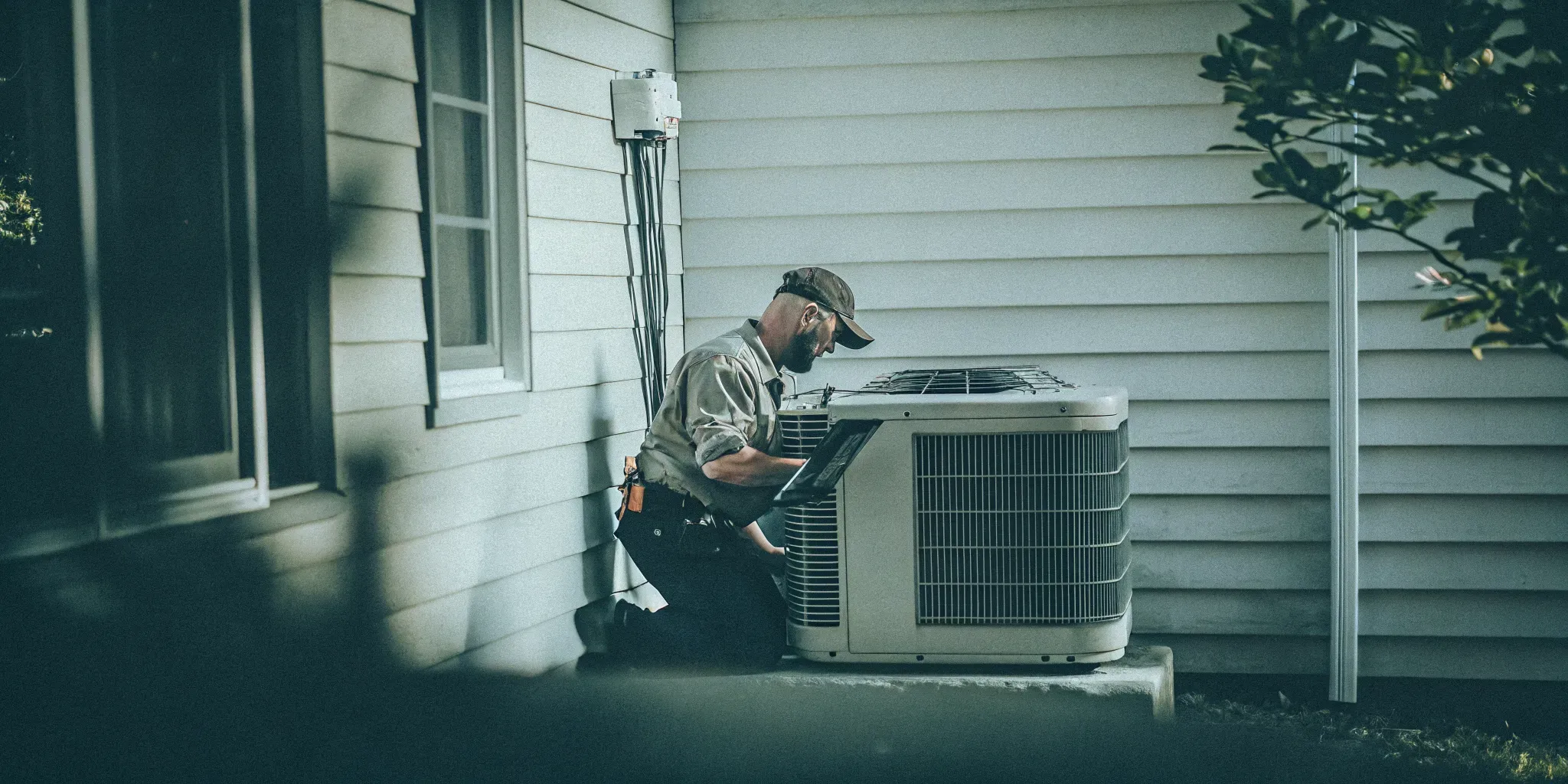 A professional NATE-certified technician inspecting an outdoor AC unit during a Maryland summer