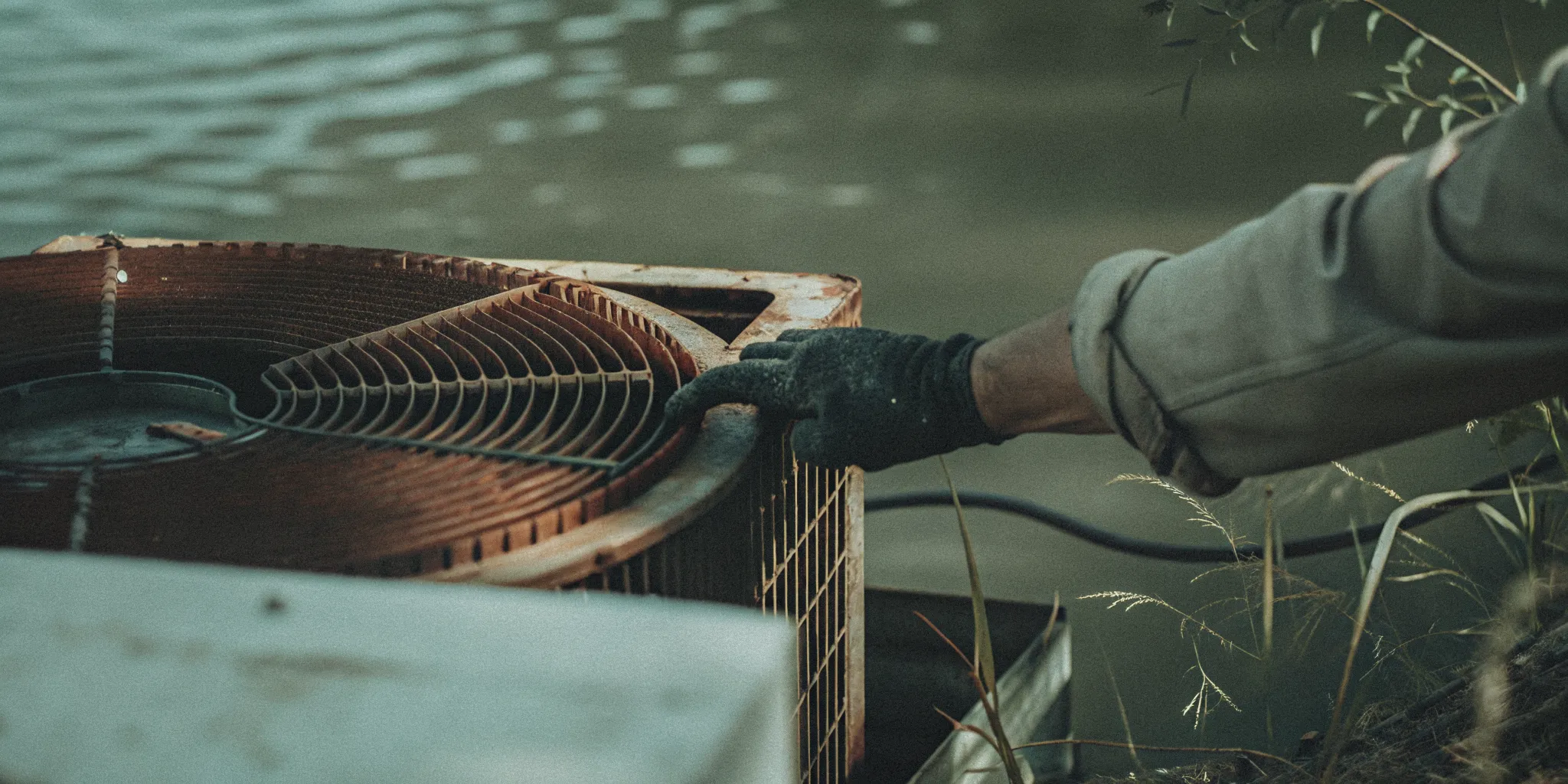 Technician inspecting slightly corroded aluminum fins on an outdoor HVAC condenser near the water in coastal Delaware