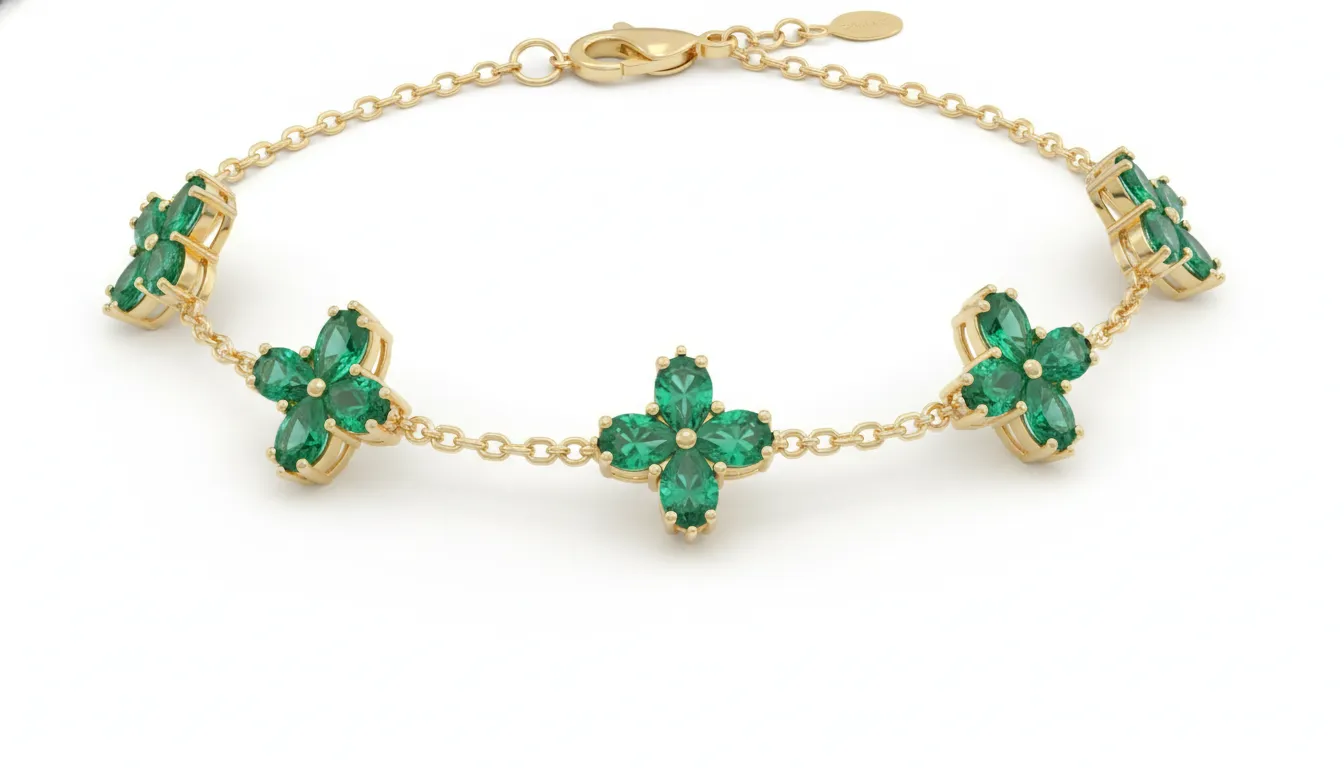 Close-up of a 14K yellow gold emerald clover station bracelet with bright green emerald stones and polished gold chain