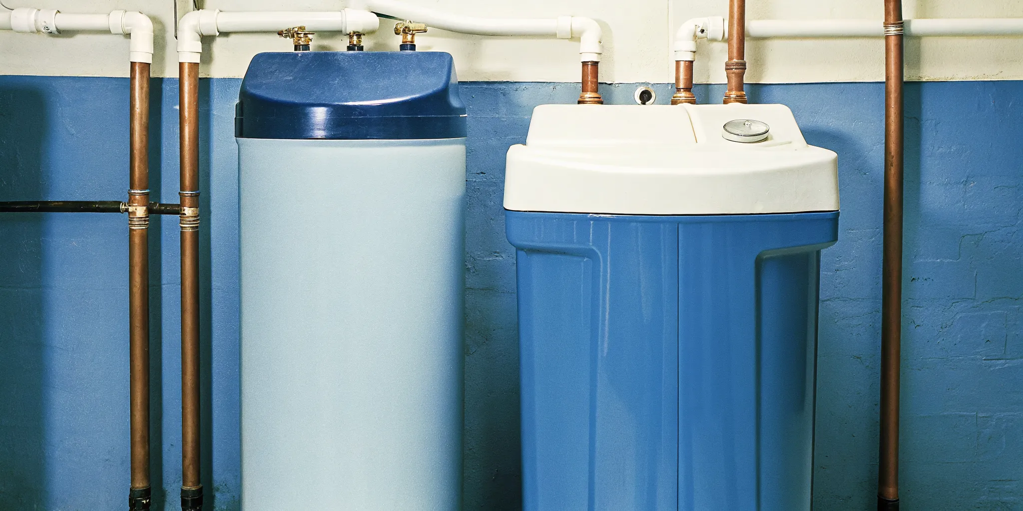 Professional water softener installation in a Minnesota basement with blue resin tanks and copper piping