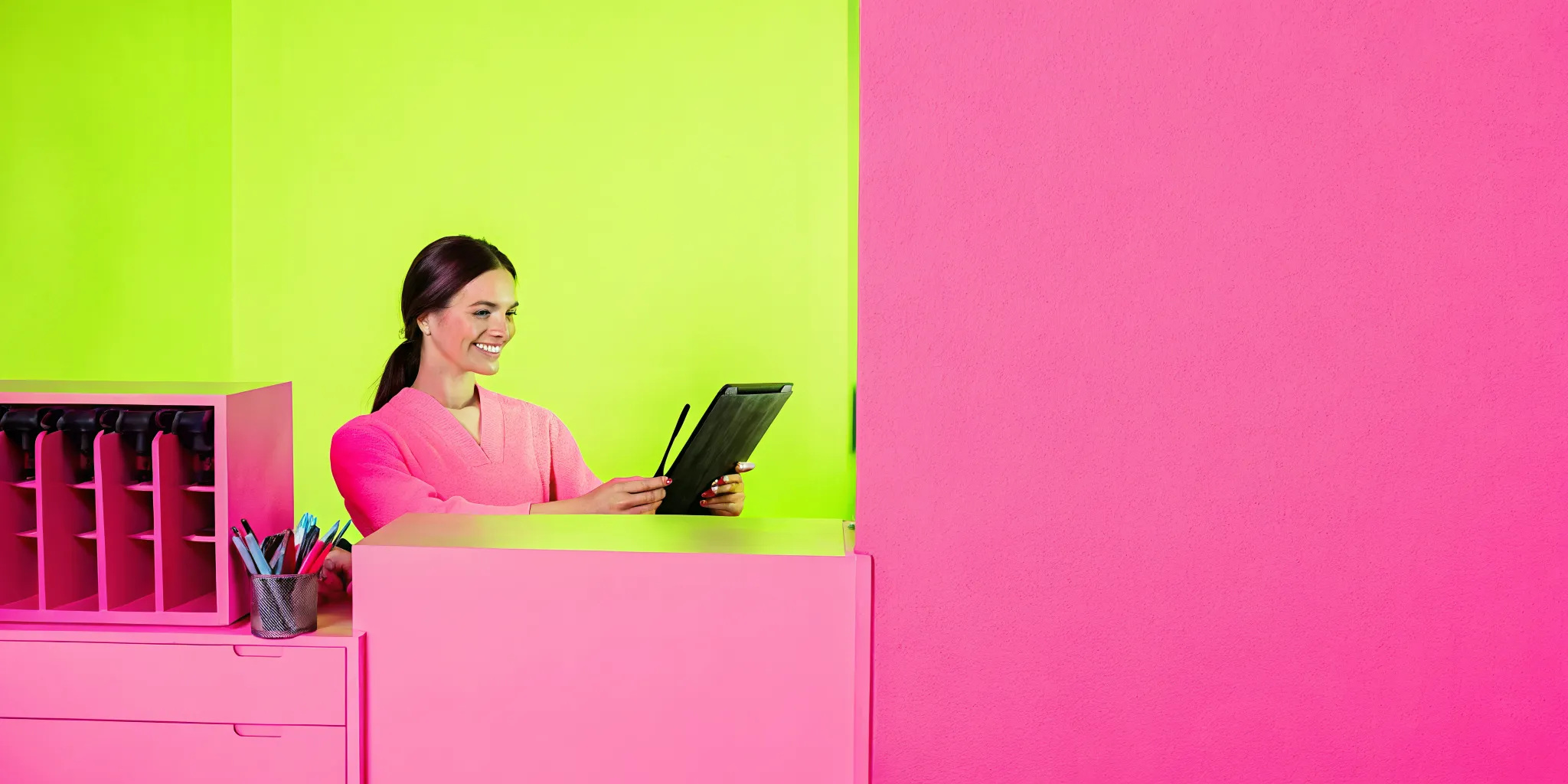 A friendly front-desk administrator using modern oral surgery front desk software to check-in a patient.