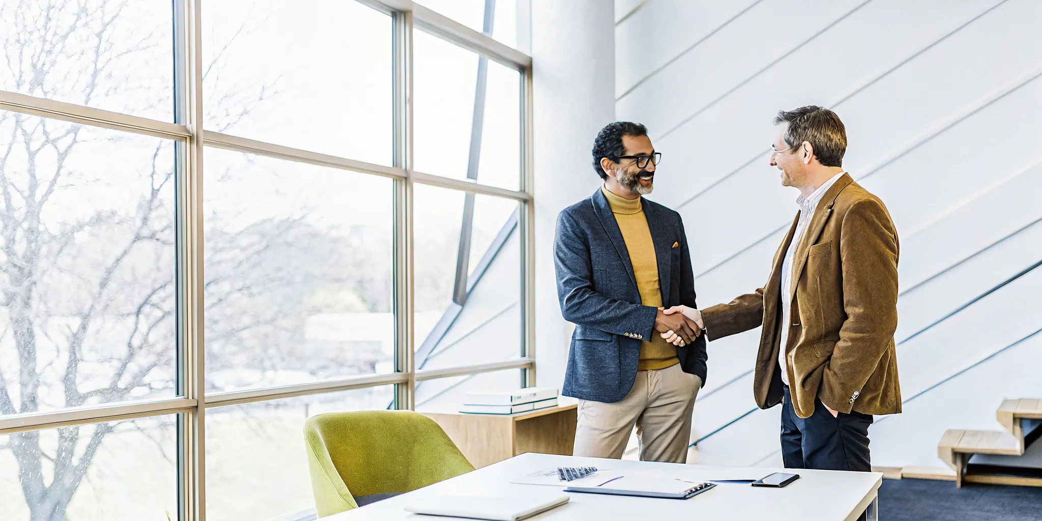 Small business owner shaking hands with a financial advisor after signing a loan agreement in a modern office