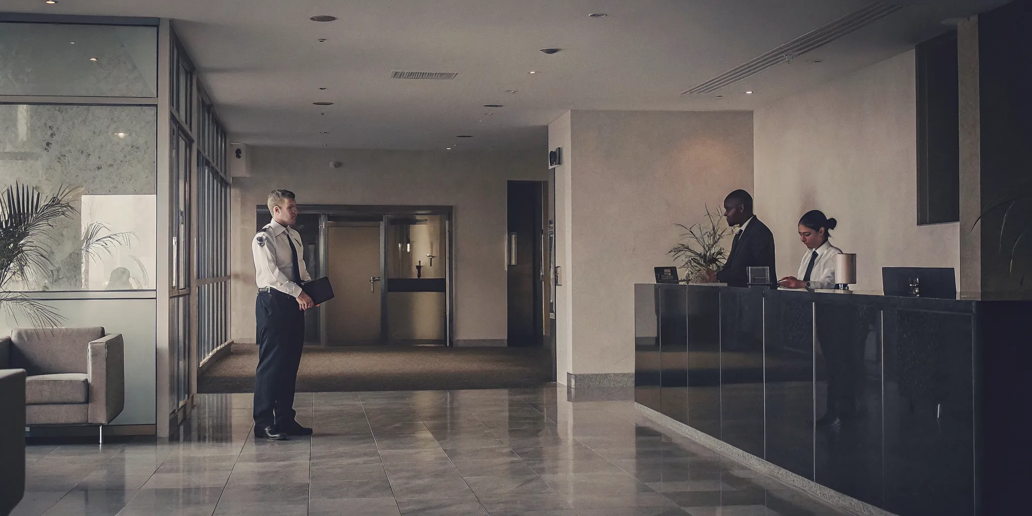 Office security guard assisting a visitor in a modern workplace lobby