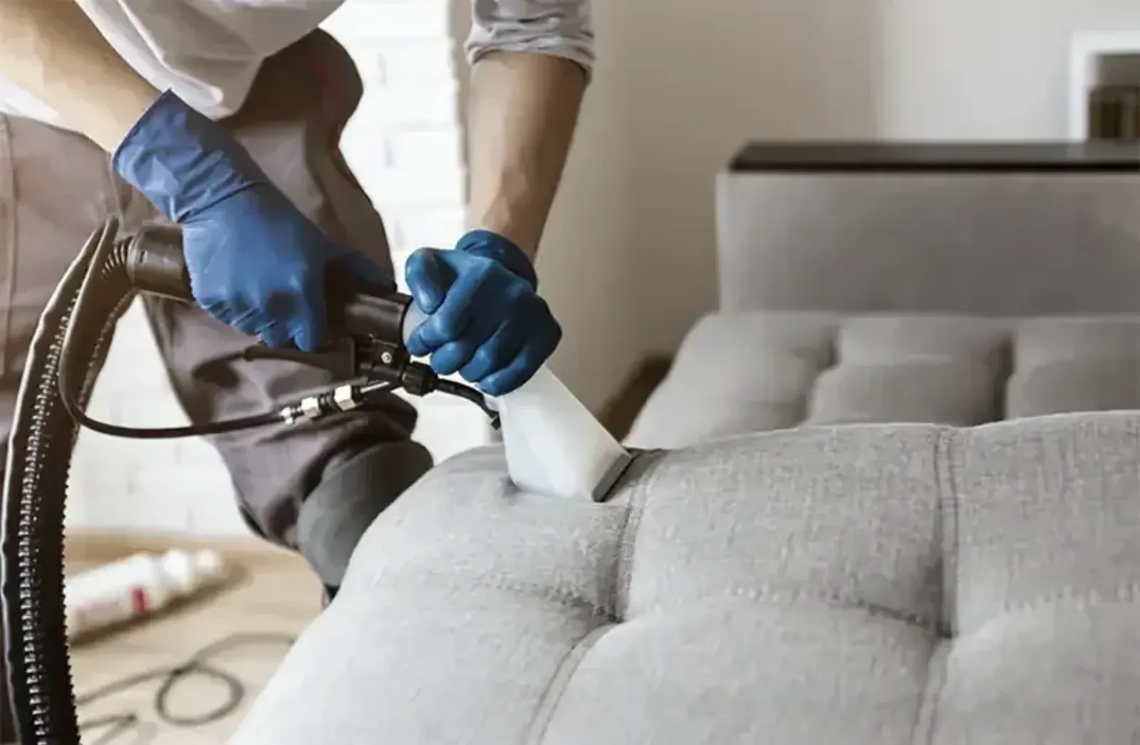 Professional upholstery cleaning equipment working on a fabric sofa in a home