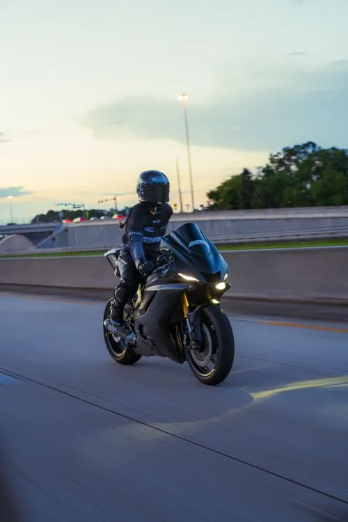 Motorcyclist riding a sport bike on a California highway at dusk, illustrating the open road and travel risks