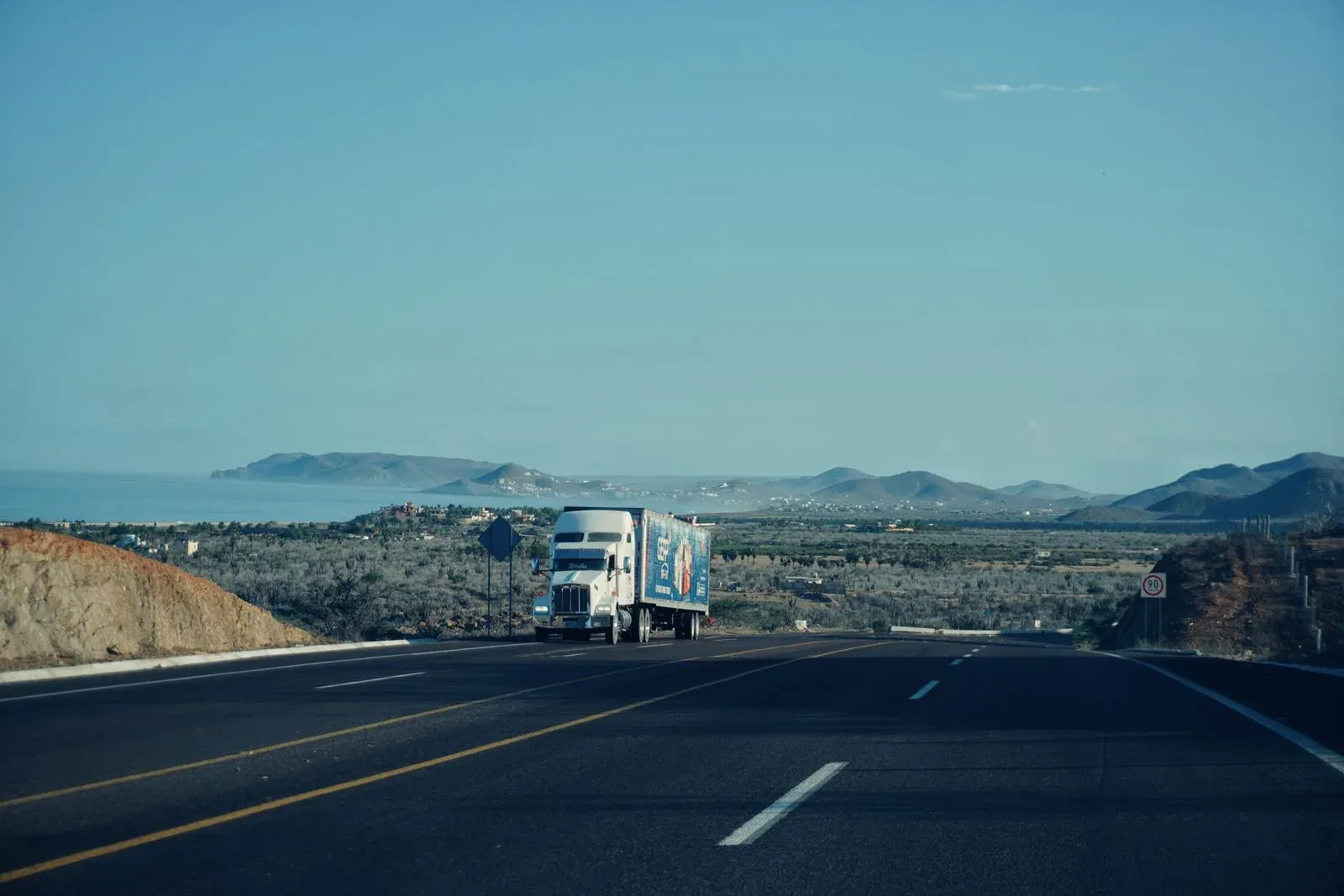 Commercial truck traveling on a California freeway with mountains in the background