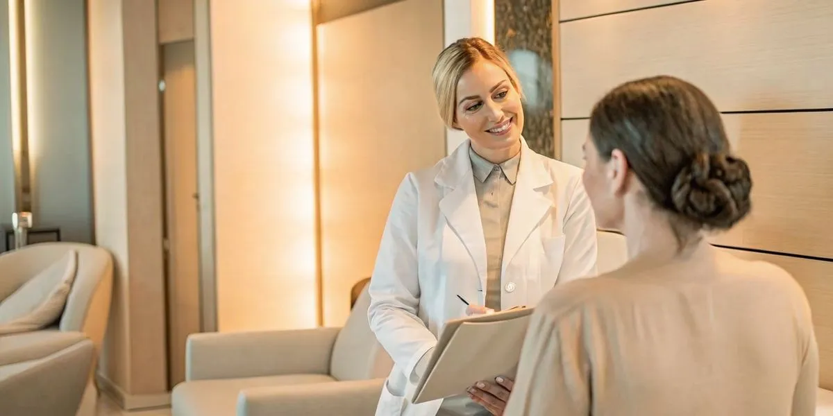 Board-certified female physician consulting with a patient in a luxury medical spa consultation room in Naples, Florida