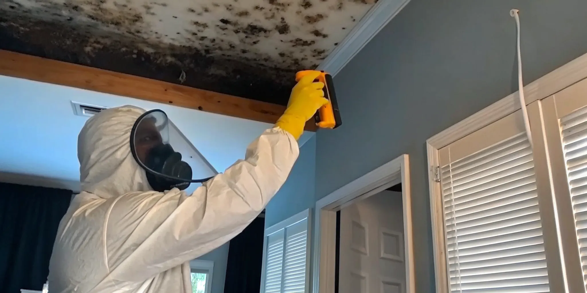 Mold remediation specialist in protective gear inspecting a Florida home interior for moisture